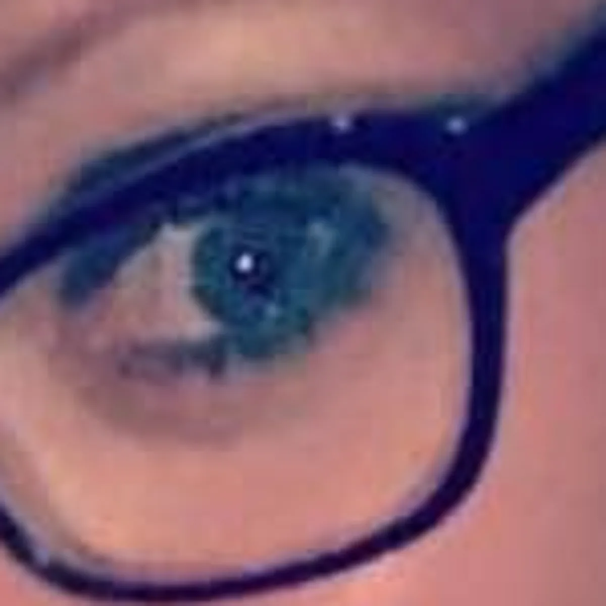 Blurry low-light close-up of an eye behind glasses — the original